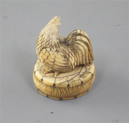 A Japanese ivory netsuke of a cockerel seated on an oval box, 19th century, 4.3cm high